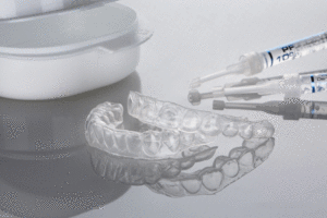 dental cap of the upper and lower jaws for whitening and syringes with whitening gel on a light background.